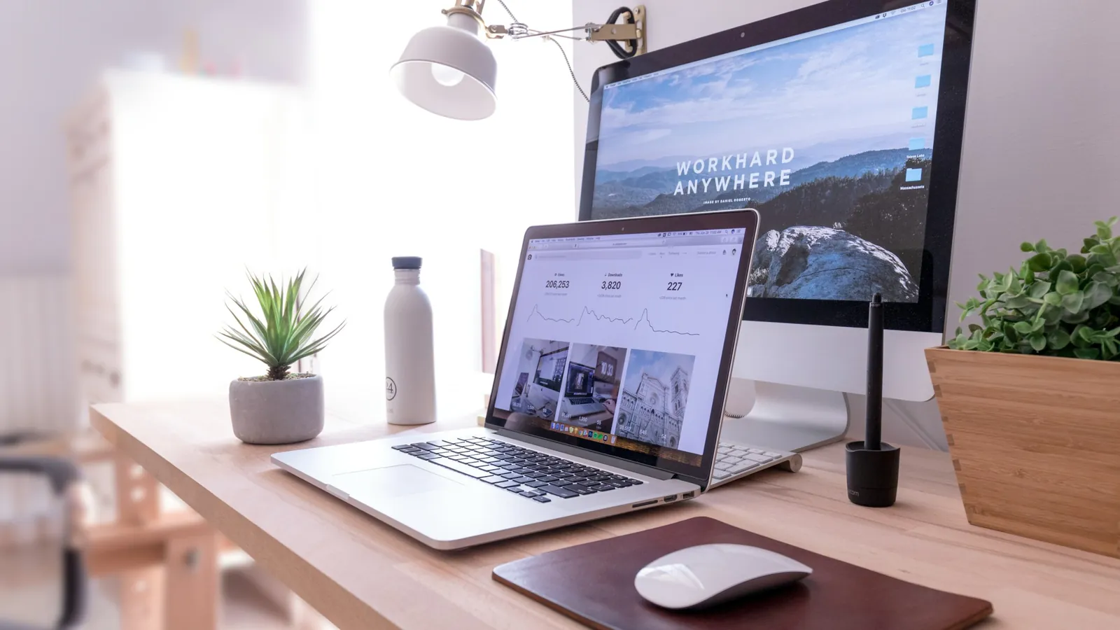 A laptop and desktop monitor on a tidy wooden desk